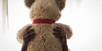 A child abuse survivor holds a teddy bear up to the light. Teddy bears can be used to facilitate emotional processing and build a therapeutic relationship for children abuse, neglect and sexual violence. (Photo: Felix Dlangamandla)