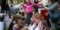 LVIV, UKRAINE - APRIL 29: A young refugee child from Eastern Ukraine grins as she walks on the arms of a group of traditionally-dressed local children as they play Ukrainian children's games on April 29, 2022 in Lviv, Ukraine. Lviv has served as a stopover and shelter for the millions of Ukrainians fleeing the Russian invasion, either to the safety of nearby countries or the relative security of western Ukraine. (Photo by Leon Neal/Getty Images)
