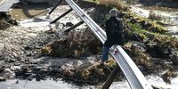 Pedestrians try to cross Spine Road in Cape Town after a section of the road surface between the N2 and Mfuleni was washed away on 15 June 2022 after a cold front moved over the Western Cape. (Photo: Gallo Images / Die Burger / Jaco Marais)