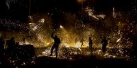 Several people attend a 'war' of firecrackers during the 'Nit de l'Alba' (Night of Dawn) of the traditional festivities of the city of Elche, eastern Spain, late 13 August 2023 (issued 14 August 2023). A total of 2,500 kilo of fireworks were used during the event, dated back to Middle Ages, to create an 'odd daybreak' lighting the sky of the city.  EPA-EFE/PABLO MIRANZO