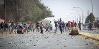 Residents throw rocks at law enforcement officials during a protest after a teenager from the area, Nathaniel Julius, was shot and killed  in Eldorado Park, Johannesburg, South Africa. 27 August 2020. Police fired stun grenades and rubber bullets to disperse protesting residents (Photo: Shiraaz Mohamed)