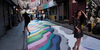NEW YORK, NEW YORK - JUNE 24: People pose for photos on the historic Doyers Street in Chinatown that has been painted over by Chilean-born street artist Dasic Fernandez during Asphalt Art Activations on Pride Month, June 24, 2021 in New York City. Doyers Street, which is also part of the city’s Open Streets program, is part of a city-wide program that looks to bring hundreds of public art installations to the streets of New York City following the pandemic lockdown which shuttered many businesses for months.  (Photo by Spencer Platt/Getty Images)