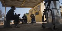 Car wash employees sit under a car port as they wait for water to be returned. (Photo: Shiraaz Mohamed)