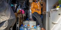 Anne Naidoo navigates her was past stored water containers that she keeps in her garage. Naidoo says she has had to replace her geyser thrice in the past one and a half years caused after her water returns. 7 September 2022. Lenasia South, Johannesburg. (Photo: Shiraaz Mohamed)