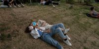 BEIJING, CHINA - MAY 15: A couple share a moment together as they relax on the grass at a local park on May 15, 2022 in Beijing, China. China is trying to contain a spike in coronavirus cases in capital Beijing after hundreds of people tested positive for the virus in recent weeks, causing local authorities to initiate mass testing, mandate proof of a negative PCR test within 48 hours to enter many public spaces, to close schools and retail stores, ban gatherings and inside dining in all restaurants, and to lockdown many neighbourhoods in an effort to maintain the country's zero COVID strategy.  (Photo by Kevin Frayer/Getty Images)