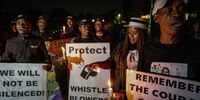 People hold banners and posters during a candlelight ceremony, held outside Babita Deokaran’s Winchester Hills home, south of Johannesburg, where she was killed a year ago. (Photo: Shiraaz Mohamed)