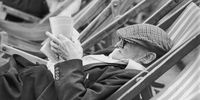 25th July 1980:  Slumped in a deckchair, an elderly man, his cap pulled down to rest on his glasses, reads a pamphlet.  (Photo by Evening Standard/Getty Images)