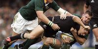 All Black centre Dan Carter is knocked to the ground in a tackle by Schalk Burger and Joe Van Niekerk (right), during the Tri-Nations rugby test won 22-16 by the Springboks at Newlands Stadium, Cape Town, South Africa, Saturday 6 August, 2005.  (Photo: Ross Land / Getty Images)