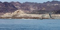 LAKE MEAD NATIONAL RECREATION AREA, NEVADA - JULY 28: A boat cruises in Boulder Basin in front of the old Basic Management Inc. intake pipe at Saddle Island, the first ever "straw" put into Lake Mead to bring water to Las Vegas, on July 28, 2022 in the Lake Mead National Recreation Area, Nevada. The white "bathtub ring" on the rocks is from mineral deposits left from when the area was submerged in water. Last week, Lake Mead dropped to just 27 percent of its capacity, with the water level at its lowest since being filled in 1937 after the construction of the Hoover Dam as a result of a climate change-fueled megadrought coupled with increased water demands in the Southwestern United States. (Photo by Ethan Miller/Getty Images)
