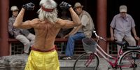 An elderly Chinese man flexes his muscles as he performs a martial arts routine on the street for onlookers on June 2, 2014 in Beijing, China. Local police moved the man along a few minutes later citing a lack of permit.  (Photo by Kevin Frayer/Getty Images)