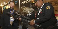 A member of India’s National Security Guard inspects a sniper rifle at an arms fair. (Photo: EPA / Rajat Gupta)