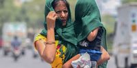 A woman holds her baby and covers her with a cloth to avoid the heatwave on the outskirts of New Delhi, India, 19 May 2022. According to the India Meteorological Department (IMD), Delhi and National Capital Region's temperature is expected to exceed 43 degrees Celsius.  (Photo: EPA-EFE / Harish Tyagi)