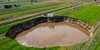SANTA MARIA ZACATEPEC, MEXICO - JUNE 09: Aerial view of a giant sinkhole on June 09, 2021 in Santa María Zacatepec, Mexico. The giant sinkhole is located 20 kilometers northwest from the capital city Puebla, the hole now measures 110 meters across its widest point, covering around 11,000 square meters and damaging a house built near the place where it appeared. Farmers of the surroundings have been affected since they are not allowed to enter their fields due to the warning perimeter set up by the authorities. (Photo by Hector Vivas/Getty Images)