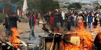 A crowd of demonstrators carry a white flag as they approach the police cordon at a settlement in Reiger Park, Johannesburg. (Photo: Nadine Hutton / Bloomberg via Getty Images)