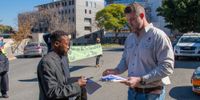 Extinction Rebellion Vaal activist Mduduzi Tshabalala (left) hands the memorandum of demands to Canyon Coal COO Clifford Hallatt outside Glubay Coal offices in Sandton on 12 July 2024. (Photo: Julia Evans)