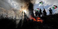 Palestinians waving Palestinian Flags stand near burning tires as they attend a march against Israeli 'Flag March' in the east of Gaza Strip, near the border with Israel, 18 May 2023. Palestinians organized their own ‘Flag March’ as a protest against Israeli right-wing 'Flag March' held in Jerusalem marking Jerusalem Day. Israeli celebration of Jerusalem Day has long been viewed by Palestinians as a provocation.  EPA-EFE/MOHAMMED SABER