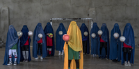 "Afghanistan’s Girl Athletes". A girls soccer team poses for a photograph while wearing a burqa.<br>Kabul, Afghanistan, 22 September 2022. A number of women and girls who used to play sports pose for portraits with the equipment of the sports they loved. They hid their identities with their burqas, the robes and hood that cover the face, leaving only a mesh to see through. They don’t normally wear the burqa, but said they sometimes choose to when they go outside and want to remain anonymous and avoid harassment. The ban on sports is just one way the Taliban has shut down life for girls and women since their takeover in August 2021. It has also barred girls from attending middle and high school; ordered all women to be thrown out of universities; severely limited women’s ability to work outside the home; and, in November 2022, the Taliban’s Ministry of Virtue prohibited women and girls from going to parks or gyms. © Ebrahim Noroozi, Iran, Islamic Republic Of, Finalist, Professional competition, Portraiture, Sony World Photography Awards 2023