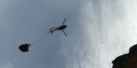 The rock in flight. A helicopter, net and a long-line cable - as well as a skilled pilot - were key to the ‘rescue’ operation. Image: Richard Webb