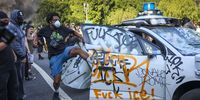 A protester vandalises a Waymo self-driving car during immigration raid protests in LA on 8 June.(Photo: Allison Dinner /  EPA-EFE)