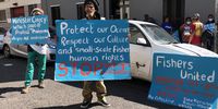 A small group of small-scale fishers and civic organisations in support of the community raise a banner to protest the now halted seismic surveying along the West Coast outside of the Cape Town High Court where the case for an urgent interdict was heard. (Photo: Onke Ngcuka)