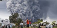 HAWAII VOLCANOES NATIONAL PARK, HI - MAY 15:  People play golf as an ash plume rises in the distance from the Kilauea volcano on Hawaii's Big Island on May 15, 2018 in Hawaii Volcanoes National Park, Hawaii. The U.S. Geological Survey said a recent lowering of the lava lake at the volcano's Halemaumau crater 'has raised the potential for explosive eruptions' at the volcano.  (Photo by Mario Tama/Getty Images)