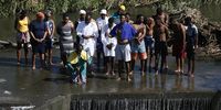 A congregation gathers at the end of their baptism ceremony to pray in the water after the cleansing ceremony to give thanks. Photo: Felix Dlangamandla