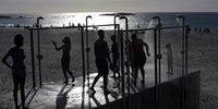 People cool down under public showers on the Camps Bay beachfront at sunset after a hot day in Cape Town, South Africa, 16 January 2016. The city and country had been experiencing its hottest weather in decades and in the interior, the worst drought in three decades. (Photo: EPA / Kim Ludbrook)