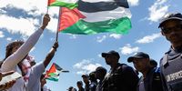Pro-palestinian protesters raise their flags at the police line. (Photo: Ashraf Hendricks)