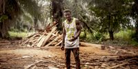 "Cut down for Charcoal, Swallowed by the Sea 07." Yakubu Issa (28), caretaker of a logging site in the Bono East region, Northern Ghana. The wood in the background is leftovers from hardwood and will be turned into charcoal. Yakubu wouldn't mind doing another job instead of the work that he is doing right now. But as there is nothing else for him to do, and it is the only way to support his family, he sees no option but to continue. © Lieven Engelen, Belgium, Shortlist, Professional, Environment, 2022 Sony World Photography Awards