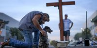 A man prays prays at the makeshift memorial for Charlie Kirk outside of the headquarters of Turning Point USA on 17 September in Phoenix, Arizona.  (Photo: Joe Raedle / Getty Images)