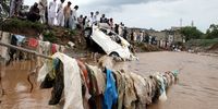 epa09373402 Vehicles and trash is seen washed away as a crowd of people watches rescue operations being carried out after floods that were caused by a cloud burst in Islamabad, Pakistan, 28 July 2021. Sector E 11 in Islamabad has been flooded with torrents that swept away cars and other vehicles after a hefty cloudburst.  EPA-EFE/SOHAIL SHAHZAD