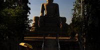 “Shadows of Buddhism.” After studying in a quiet place near the Buddha statue, the monk often returns to the hut with an umbrella for shade, here representing both a sunshade and the shade of Buddhist serenity. © Sean Channal, Cambodia, Winner, National Awards, Street Photography, 2022 Sony World Photography Awards