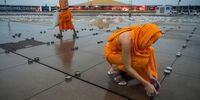 BANGKOK, THAILAND - JULY 24: Buddhist monks prepare thousands of candles on the ground to be lit up during Asalha Puja Day celebration at Wat Phra Dhammakaya Buddhist temple on the outskirt of Bangkok on July 24, 2021 in Pathum Thani, Thailand. Asalha Puja Day (also called Dharma Day) is celebrated by Theravada Buddhists to mark Buddhas' first sermon following his enlightenment. As Thailand continues to battle a third wave of the coronavirus pandemic, Wat Phra Dhammakaya temple invited devotees to participate in the ceremony online. (Photo by Sirachai Arunrugstichai/Getty Images)