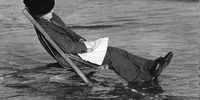 7th May 1936:  Photographer George W. Hales asleep in a deckchair, and unaware of the incoming tide at Barry Island, near Cardiff in Wales.  (Photo by Richards/Fox Photos/Getty Images)