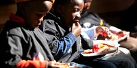 Disadvantaged youth eat a free lunch while at a camp run by the South African Business Coalition on HIV/AIDS (SABCOHA) on June 21, 2010 in Soweto, South Africa. Five such camps spread across the country are funded jointly by South African businesses and the U.S. government. The month-long program is designed to educate some 1,500 children on HIV/AIDS prevention as well as help parents with daycare during the World Cup school holiday. Children in the camps are also taught soccer, dance and theater and are given two full meals a day.  (Photo: John Moore / Getty Images)