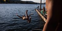 A swimmer dives into the Willamette River from a dock at Sellwood Riverfront Park during a heatwave in Portland, Oregon, U.S., on Monday, June 28, 2021. The rare and powerful heat wave that's shattering records across the U.S. Northwest is taking a bruising toll on the region's infrastructure, buckling highways, hobbling public transit and triggering rolling power outages. Photographer: Maranie Staab/Bloomberg via Getty Images
