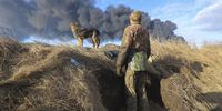 epa09788439 A Ukrainian serviceman and his dog stands in a position looking at smoke from a burned petroleum storage depot behind after a Russian missile attacked near Kiev, Ukraine, 27 February 2022. Russian troops entered Ukraine on 24 February prompting the country's president to declare martial law and triggering a series of announcements by Western countries to impose severe economic sanctions on Russia.  EPA-EFE/ALISA YAKUBOVYCH