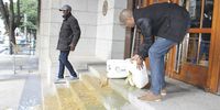Loyiso Nkohla empties the contents of a porta-loo tank on the steps of the provincial legislature on Monday. (Photo: Nombulelo Damba/WCN)