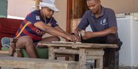 From left to right: Juwayne Arries (24) and Fareldo Maksella (26) play dominoes on the stoep of Arries’ home in Klaarstroom on the morning of 13 October 2021. (Photo: Victoria O’Regan)