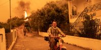 A local drives away from a wildfire approaching the village of Gouves, on the island of Evia, Greece, on Sunday, Aug. 8, 2021. Thousands of residents were evacuated from the Greek island of Evia by boat after wildfires hit Greeces second biggest island. Photographer: Konstantinos Tsakalidis/Bloomberg via Getty Images