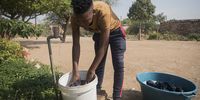 Water is seen trickling out of a tap as a man washes clothing. (Photo: Shiraaz Mohamed)