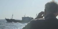 Ian Urbina watches a Chinese vessel through binoculars while at sea in waters between North and South Korea. May 2019 (Photo: The Outlaw Ocean Project/ FábioNascimento)
