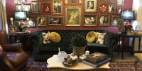 A wall of Victorian portraits, prints and miscellania, each framed individually with eclectic verve, behind a dark teal Chesterfield couch. (Photo: Tony Jackman)
