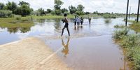 A group of boys cross over an over flooded paved road in Ntswanahatshe village, Taung North West province.Photo:Tiro Ramatlhatse