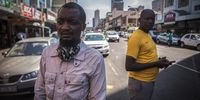 Prince Muhikuzi (left) stands on Bertha Mkhize Street, formerly known as Victoria Street, hours after the attack took place. Foreign nationals are now seeking the help of the UNHCR and say they are not being protected by the SAPS. (Photo: Shiraaz Mohamed)