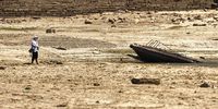 A man fishes in a puddle of thge dried Poyang Lake, Jiangxi Province, China, 24 August 2022. Severe drought exposed the ancient Luoxingdun stone island in the middle of dried Poyang Lake in East China. It was the first time in 71 years that the historic island could be fully seen.  (Photo: EPA-EFE / Alex Plavevski)
