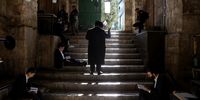 Israeli police officers guard the door leading to Al-Aqsa Mosque compound as Orthodox Jews pray and read from the book of Eicha (Book of Lamentations) to mark Tisha B'av, near The Western Wall, in the Old City of Jerusalem, 27 July 2023. In Judaism, the Tisha B'Av is an annual fast day to mark the destruction of the first and the second temple by the Babylonian and the Roman Empires in Jerusalem. During Tisha B'av, Ultra-Orthodox Jews stay up all night and sleep at the Western Wall as they recite lamentations focusing on the destruction of the ancient temple, that was located on the other side of the ancient wall, on the Temple Mount.  EPA-EFE/ABIR SULTAN