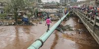 A man walks on a huge pipeline over a flooded river as pedestrians (R) gather on a bridge to look at damaged homes following a night of heavy rainfall and the overflowing of Gitathuru river, in the Ngondo village, in Mathare, Nairobi, Kenya, 24 April 2024. Kenya's meteorological department predicts more heavy rainfall this week, as floods continue to destroy properties in various parts of the country. According to the Kenya Red Cross Society, at least 103,485 people have been affected by the March-May long rains that continue to rise, including 40,265 people displaced, as of 18 April 2024.  EPA-EFE/DANIEL IRUNGU