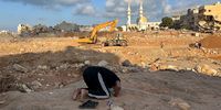 A man prays near rescue teams working at a flood-affected area in the port city of Derna, eastern Libya, on 16 September 2023. Unprecedented floods struck Libya after Mediterranean Storm Daniel made landfall on 10 September.  (Photo: EPA-EFE / Stringer)