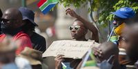 A man holds the South African flag while listening to a speech at Church Square.<br>Photo / Shiraaz Mohamed